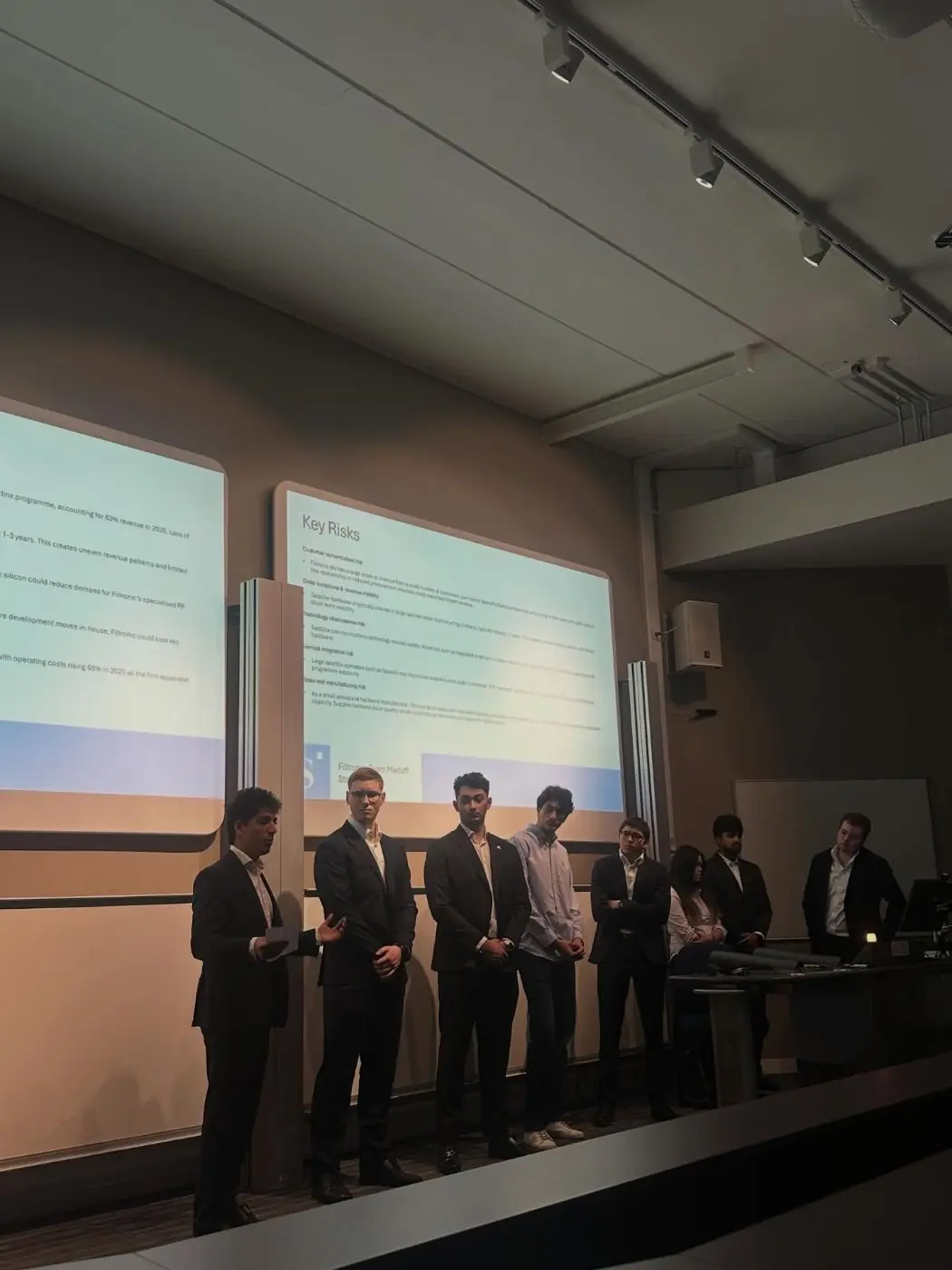 A team in suits presenting a stock pitch on stage